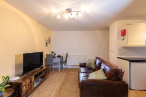 a living room with a couch and a flat screen tv at Heather Cottage - a beautiful cosy cottage for couples in Snainton