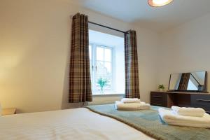 a bedroom with a bed with a mirror and a window at Heather Cottage - a beautiful cosy cottage for couples in Snainton +3 photos