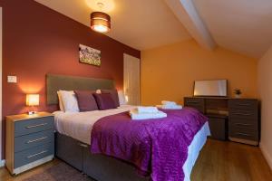 a bedroom with a large bed with a purple blanket at Lavender Cottage - a beautiful quirky family cottage in Snainton