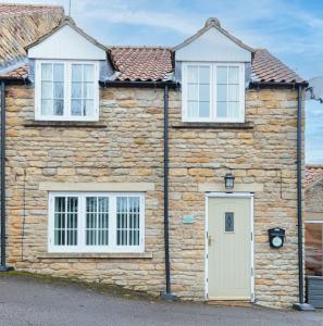 a stone house with two windows and a white door at Sunflower Cottage - a charming family cottage in Snainton
