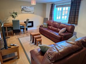 a living room with a leather couch and a table at Dandelion Cottage - a gorgeous family cottage in Snainton