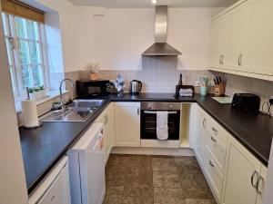 a kitchen with white cabinets and black counter tops at Dandelion Cottage - a gorgeous family cottage in Snainton