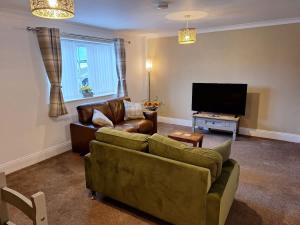 a living room with a couch and a flat screen tv at Sunflower Cottage - a charming family cottage in Snainton