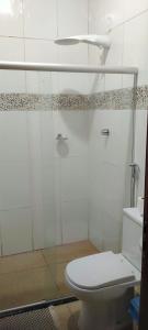 a bathroom with a toilet and a glass shower at Casa formosa in Porto Seguro