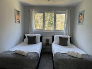two twin beds in a room with a window at 3 Bed House Close to Gatwick in Crawley