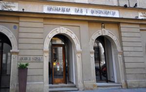 a building with three arched windows and a hotel sign at Hotel Stary in Kraków