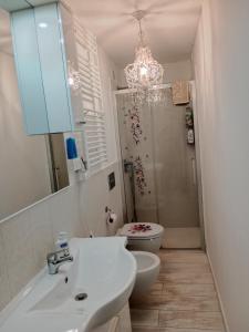 un bagno con lavandino, servizi igienici e lampadario pendente di Appartamento bilocale ERICA a Monteriggioni Altre 6 foto
