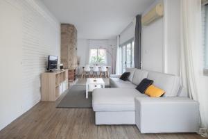 Una sala de estar blanca con un sofá y un televisor. en Marina beach Castelldefels, en Castelldefels