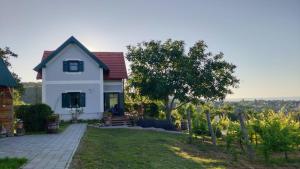 a white house with a tree in the yard at Panorámaház Lovason in Lovas