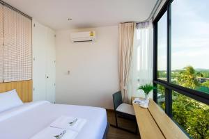 a bedroom with a bed and a large window at Condo Near Bangtao Muay Thai & MMA in Ban Thalat Choeng Thale