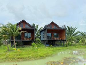 Deux maisons sur une colline à côté d'une nappe d'eau dans l'établissement Chom Nakhon Resort, à Tha Sala 19 autres photos