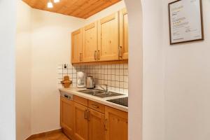 a kitchen with wooden cabinets and a sink at Alpenblick Tilly - Fewo Eibsee 1 in Krün