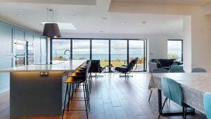 a kitchen with a bar with chairs and a living room at 105 The Beach House in Penrhyn Bay