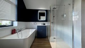 a bathroom with a tub and a glass shower at 105 The Beach House in Penrhyn Bay +27 photos