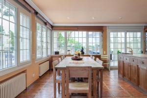 cocina grande con mesa de madera y ventanas en Villa Drago, en Castelldefels