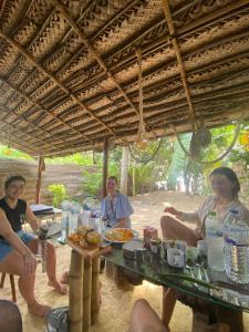 a group of people sitting around a table with food at Village Cottage in Dickwella