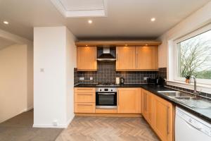 a kitchen with wooden cabinets and a window at 3 Bed House-Free Parking-6Beds in Cumbernauld