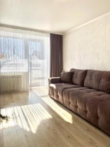 un soggiorno con divano marrone e ampia finestra di Джамбула 177 a Kökşetaw