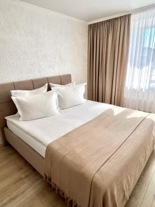 una camera da letto con un grande letto con lenzuola bianche e una finestra di Джамбула 177 a Kökşetaw