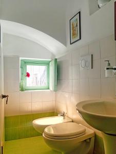 un bagno con lavandino, WC e finestra di Casa Antica Cibbun a Martina Franca