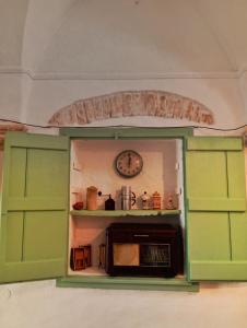 una cucina con armadi verdi e un orologio sul muro di Casa Antica Cibbun a Martina Franca Altre 4 foto