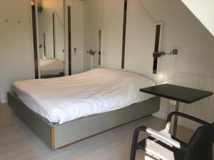Bett in einem Zimmer mit einem Tisch und einem Stuhl in der Unterkunft Hostellerie Klokhof in Kortrijk