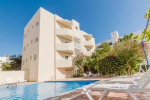 un hotel con piscina frente a un edificio en Apartamentos Timon - Emar Hotels, en Es Pujols