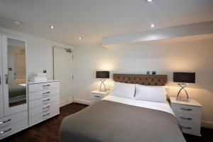 a bedroom with a bed with two lamps and a mirror at Bloomsbury Residences in London