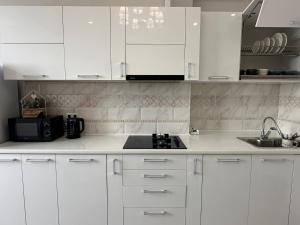 a white kitchen with white cabinets and a sink at Lovely house in the city center in Bishkek