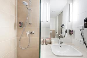 ein Bad mit einer Dusche und einem Waschbecken in der Unterkunft Ibis Styles Konstanz in Konstanz