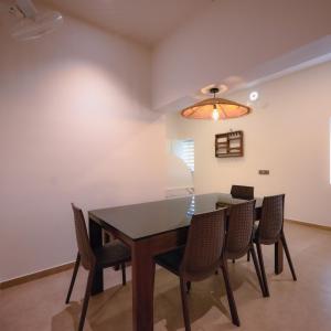 a dining room with a table and chairs at Ohstayz Villa De Estate 64 in Kizhake Chālakudi