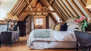 a bedroom with a large bed in a attic at Lavish Tudor Estate & Gardens - Sleeps 20 in Hales