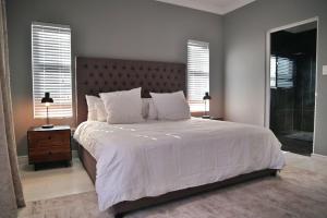 a bedroom with a large bed with white sheets and pillows at Exquisite Family Cape Villa Pool and Fire Pitt in Cape Town +35 photos