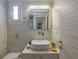 a white bathroom with a sink and a mirror at Plateia House Mykonos in Mikonos +50 photos