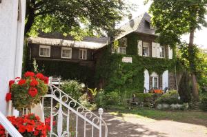 ein Haus voller Efeu mit einem Zaun und Blumen in der Unterkunft Pension Johanna in Aßmannshausen