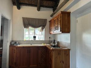 Una cocina con armarios de madera y un fregadero y una ventana. en Gratitude Wellness Village - The Cottages, en Droëvlakte 25 fotos más