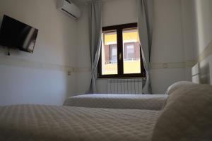 a bedroom with two beds and a tv and a window at MariSte Apartment in Parghelia