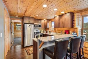 una cocina con armarios de madera y una barra con sillas en Amazing Secluded Cabin On 10 Acres, Close To Breck, en Fairplay