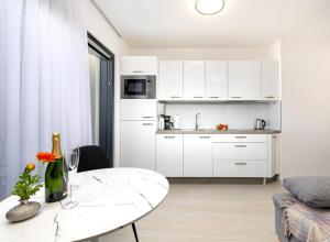 eine Küche mit weißen Schränken und einem weißen Tisch im Wohnzimmer in der Unterkunft Luxury Studio Rim Tim in Malinska
