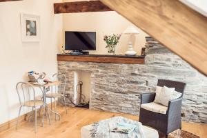 a living room with a stone fireplace with a tv at ApartmentSleeps3-Garden-HotTub-Parking in Padstow