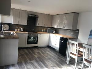 a kitchen with white cabinets and a table and chairs at Littlecross Cottage in Barnstaple