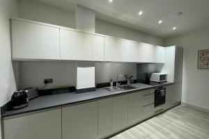 a kitchen with white cabinets and a sink and a microwave at 1 bed-Sleeps 4-Town Centre-10 min to Ascot- Pets in Bracknell