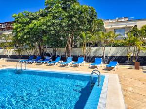 ein Swimmingpool mit Liegestühlen neben einem Gebäude in der Unterkunft Pearl of Amarilla Golf - Luxury 3 Bedroom Villa with heated pool & ocean view in San Miguel de Abona
