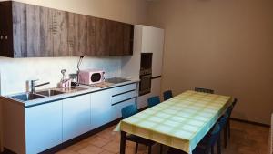 a kitchen with a sink and a table with a microwave at Casthello Ostello di Vallecamonica in Breno