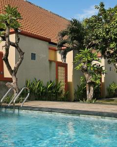 a swimming pool in front of a house at Gelis Gede Cottages in Uluwatu