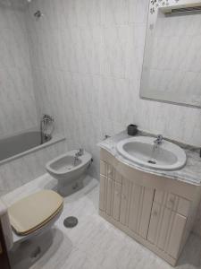 Un baño blanco con inodoro y lavabo. en Cristel, en Puentecesures