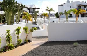einen weißen Zaun mit Bäumen und Häusern im Hintergrund in der Unterkunft CASA VELA by Mhousing in Playa Blanca