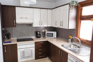 eine Küche mit weißen Schränken und einer Spüle und einer Mikrowelle in der Unterkunft CASA VELA by Mhousing in Playa Blanca
