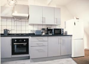a kitchen with white cabinets and a white refrigerator at The Coastal Gateway, 3 bedrooms, 5 beds,, central location in Eastbourne