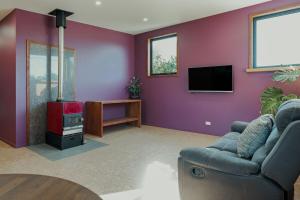 sala de estar con paredes de color púrpura, sofá y TV en Hidden Retreat, en Royal Park 6 fotos más